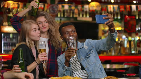 Friends-take-pictures-on-the-phone-at-the-bar-make-a-shared-photo-on-the-phone.-Party-with-friends-at-the-bar-with-beer.